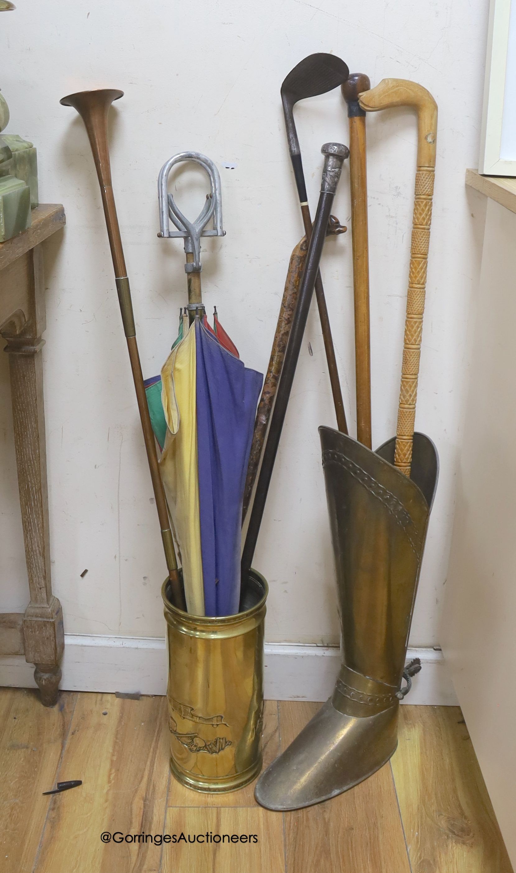 A Chinese white metal topped cane hunting horn, dog head cane, shooting stick and a Japanese embossed shell case, walking sticks, a golfing putt and a boot shaped umbrella stand